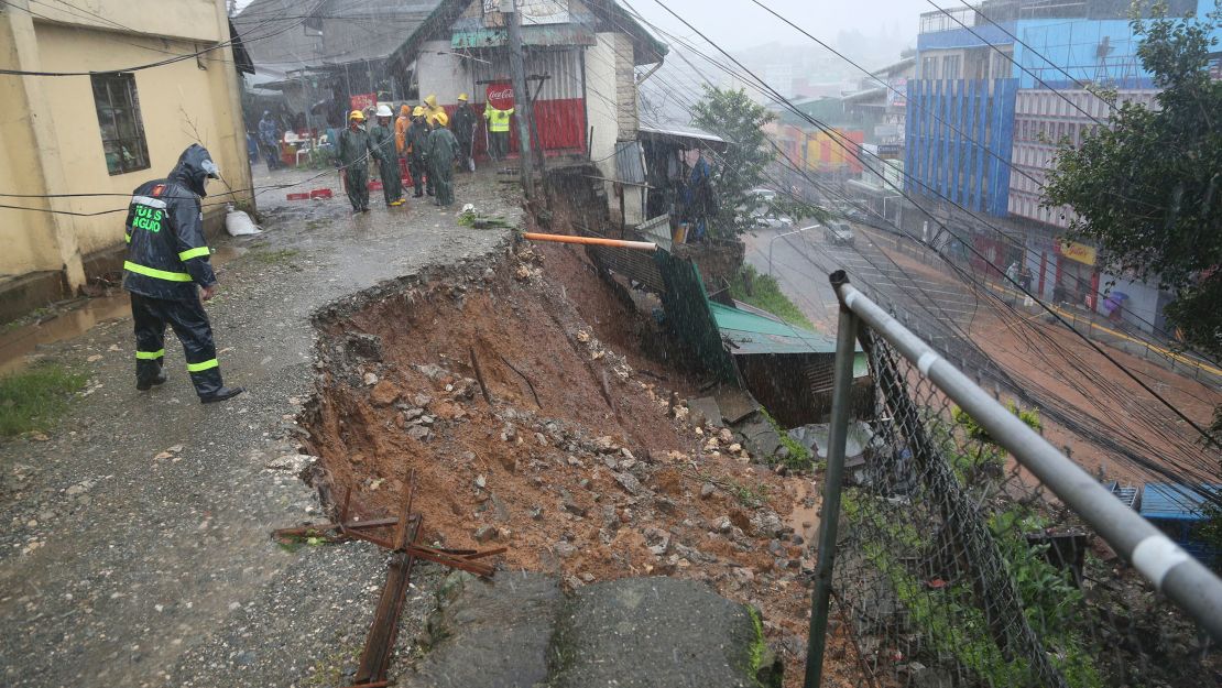 A police officer checks a landslide caused by the typhoon at a residential area in Baguio City, northern Philippines.