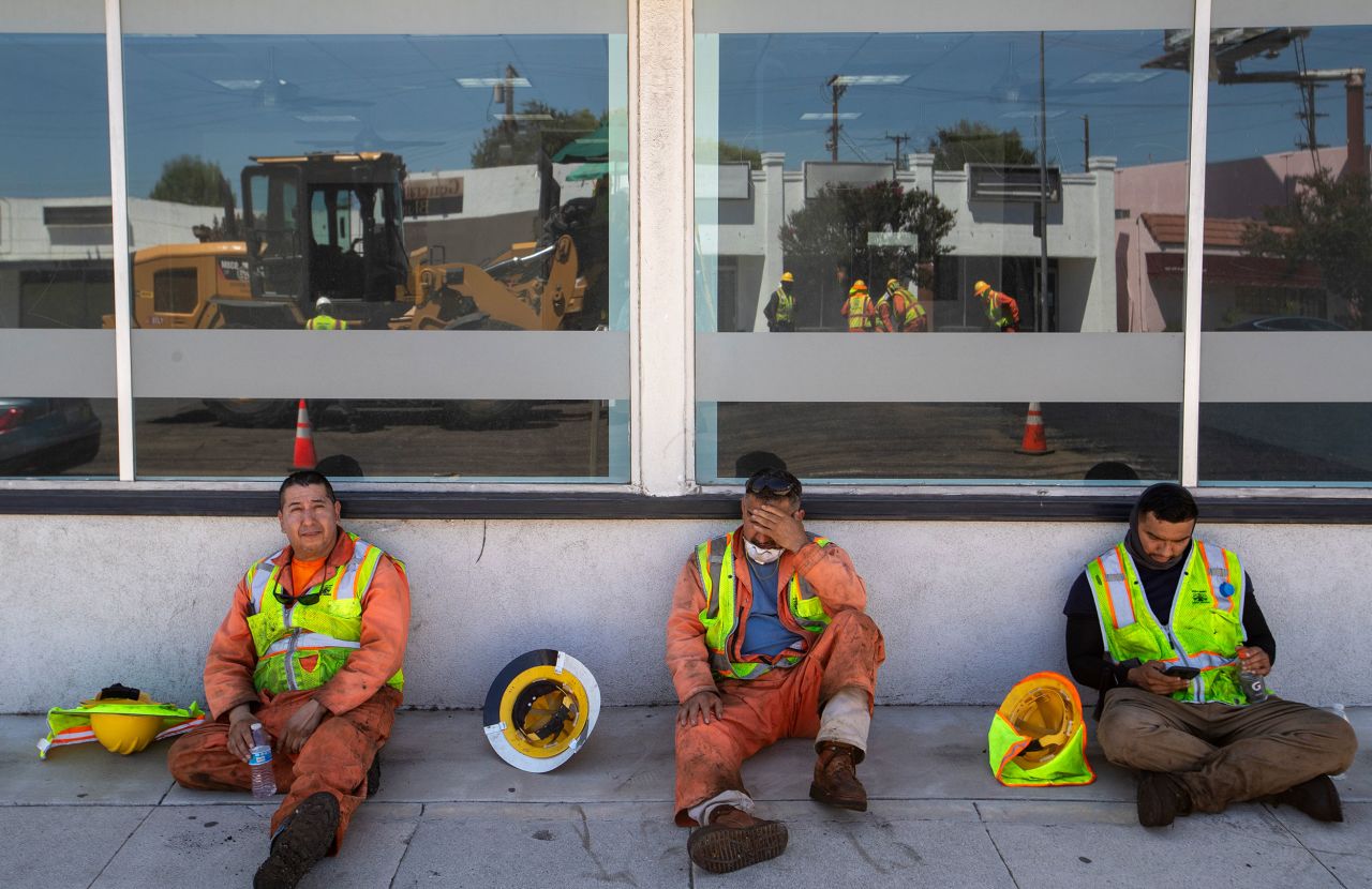 City workers take a break in the shade of a nearby storefront as they lay down new pavement in Woodland Hills, California, on July 27.