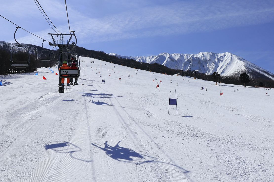 Rear view of skiers on ski lift going up to the top of snowy mountain at cold sunny day. People enjoy skiing and snowboarding on slope with slalom flags, Snow covered mountain peaks in the background,Wide angle view.
Daisen White Resort, Ski hills on the northern slopes of Mt.Daisen,the highest mountain (volcanic mountain)in Chugoku region in Japan.