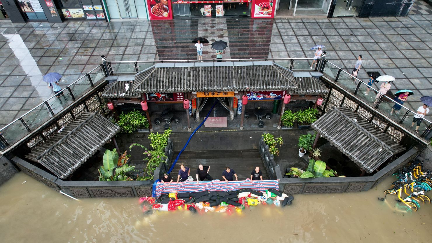 Workers stand behind a flood protection barrier at the entrance of a restaurant on a flooded street on in Fuzhou, Fujian Province of China on July 29.