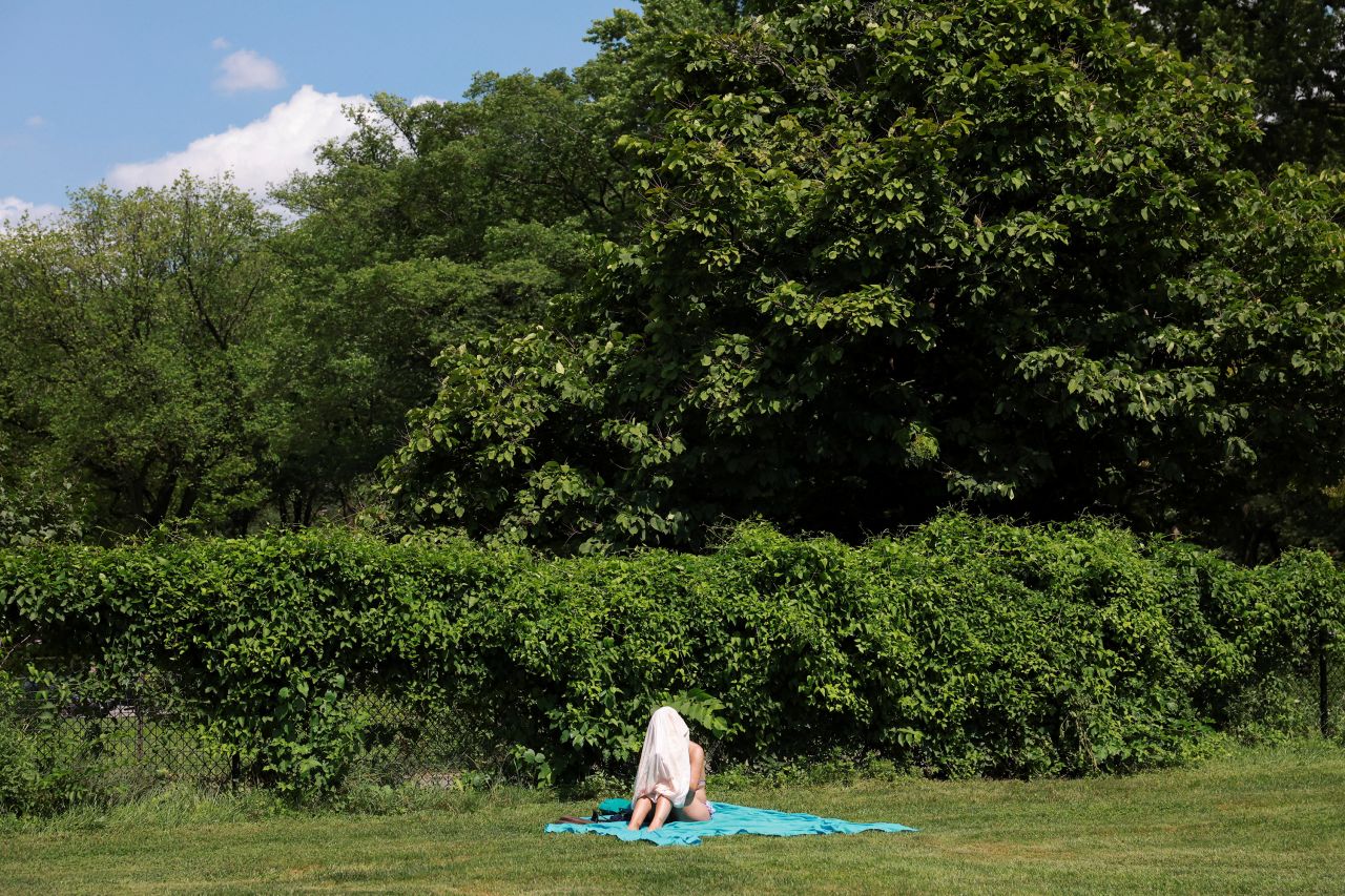 A person hides under a face cover in Manhattan's Central Park during a heat wave in New York on Friday, July 28.