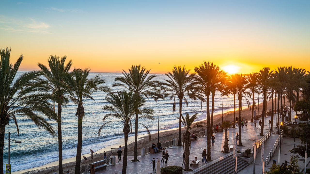 Marbella sunset beach in Playa de la Fontanilla in Malaga province of Spain. Fontanilla is the mostpopular beach with a promenade just downtown Marbella city and beautiful palm trees. Just beside the city marina dock.