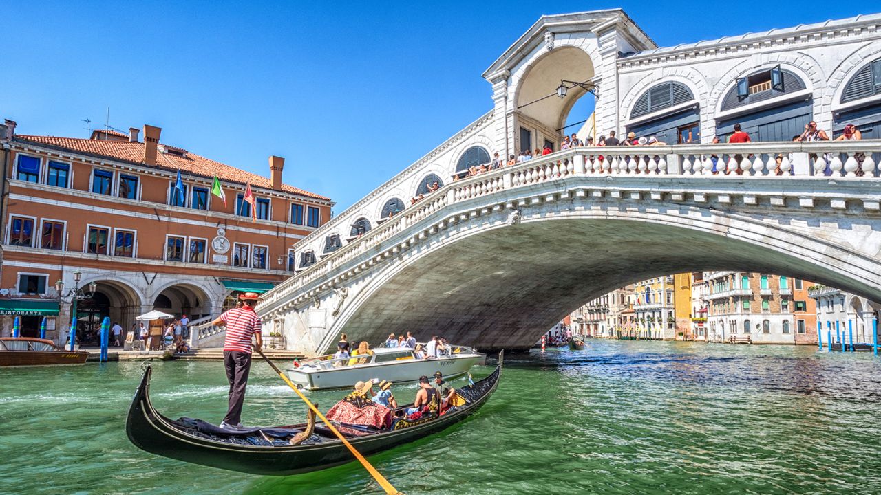 Venice, Italy -- August 15, 2017:  Gondola with tourists on Gran Canal with Rialto Bridge, Venice
