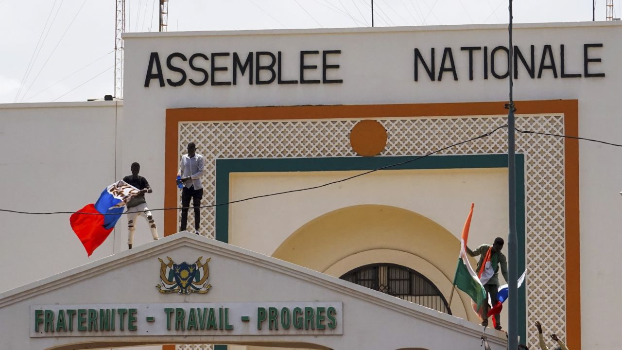 People with Niger and Russia flags climb the gate to the National Assembly building during a protest in Niamey. 