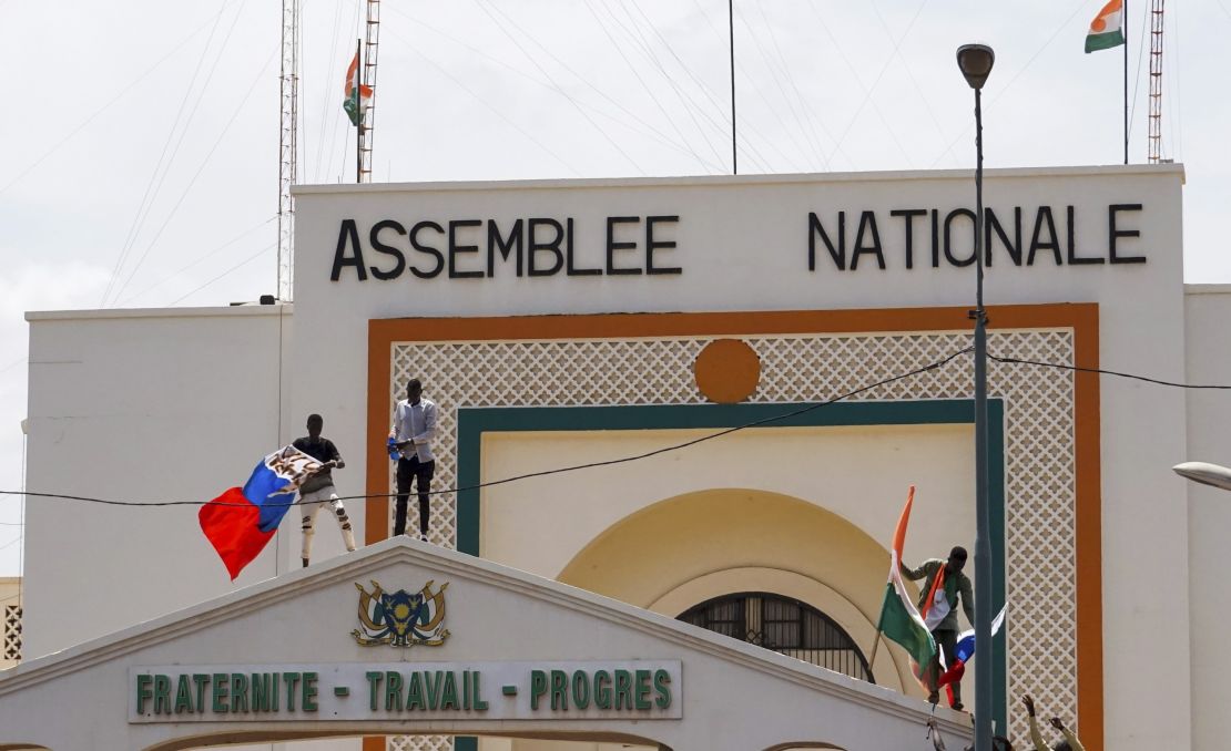 People with Niger and Russia flags climb the gate to the National Assembly building during a protest in Niamey. 
