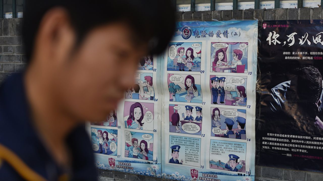 Мъж минава покрай пропаганден плакат, предупреждаващ жителите на Китай за чуждестранни шпиони, в Пекин на 23 май 2017 г.