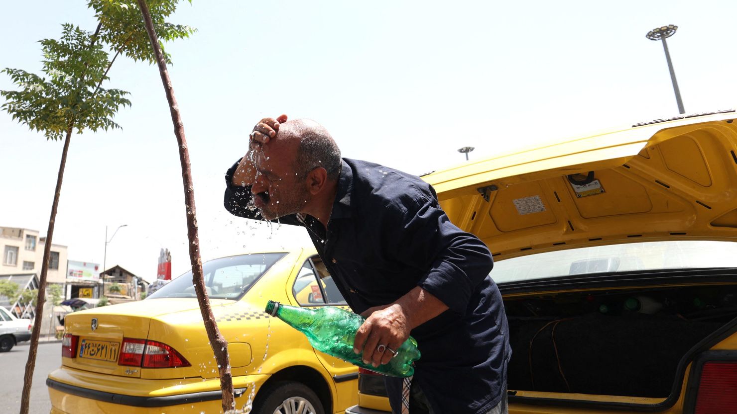 A taxi driver splashes water on himself to cool down during the heat surge in Tehran, Iran August 2, 2023.