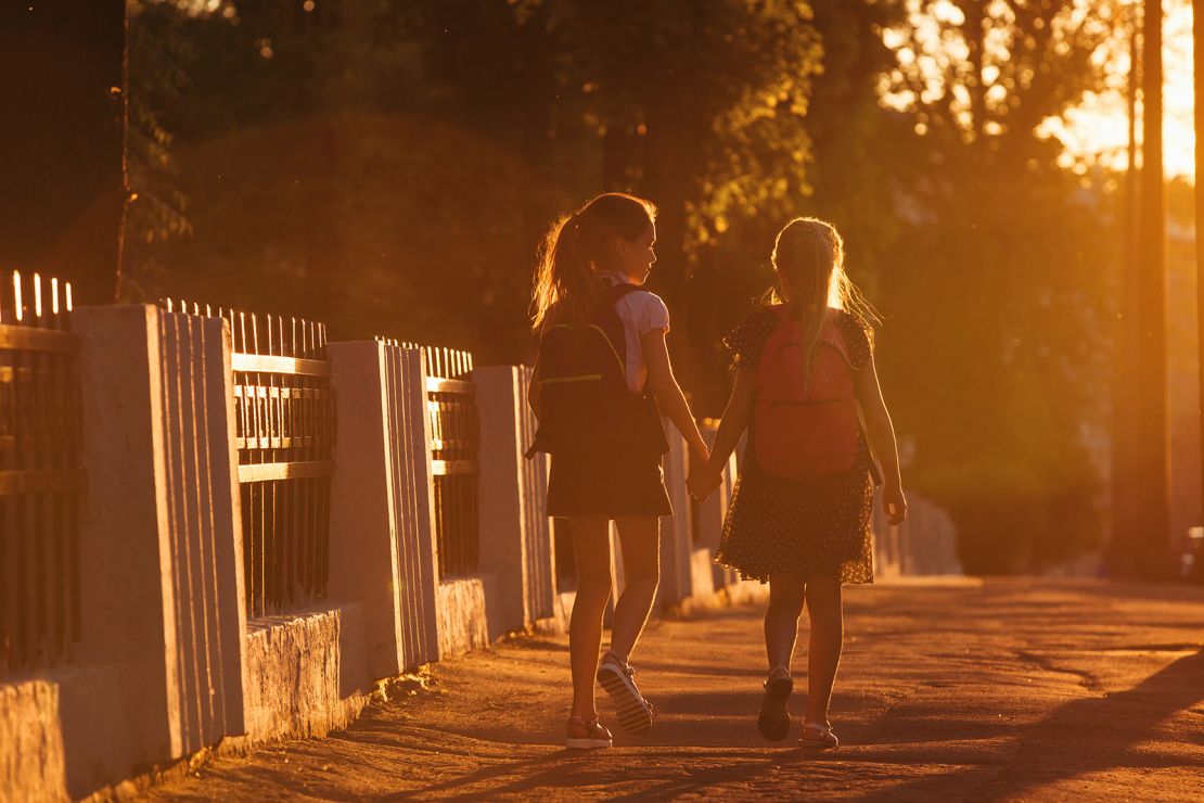 Two child girls is walking with a school bag in sunny day
