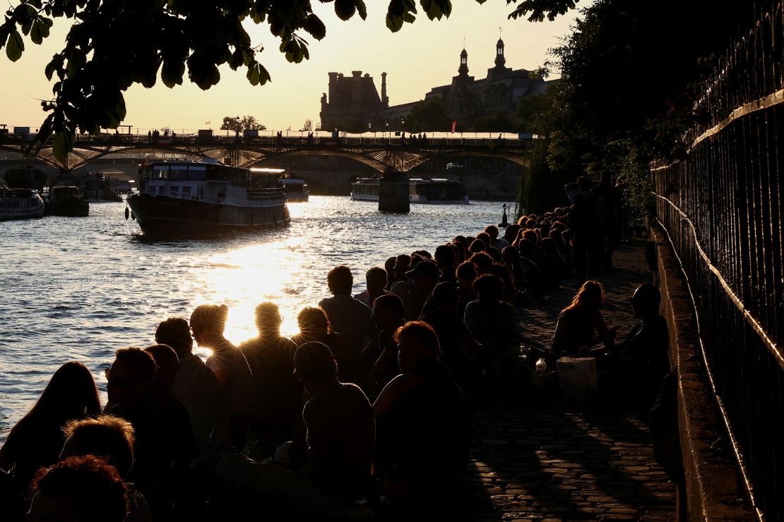 People enjoy the sunset on a bank of the River Seine, in Paris, France, in June.