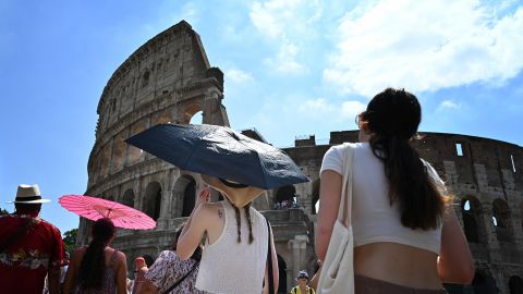 Tourists shelter from the sun with umbrellas near the Colosseum in Rome, on July 14, 2023, as Italy is hit by a heatwave. 