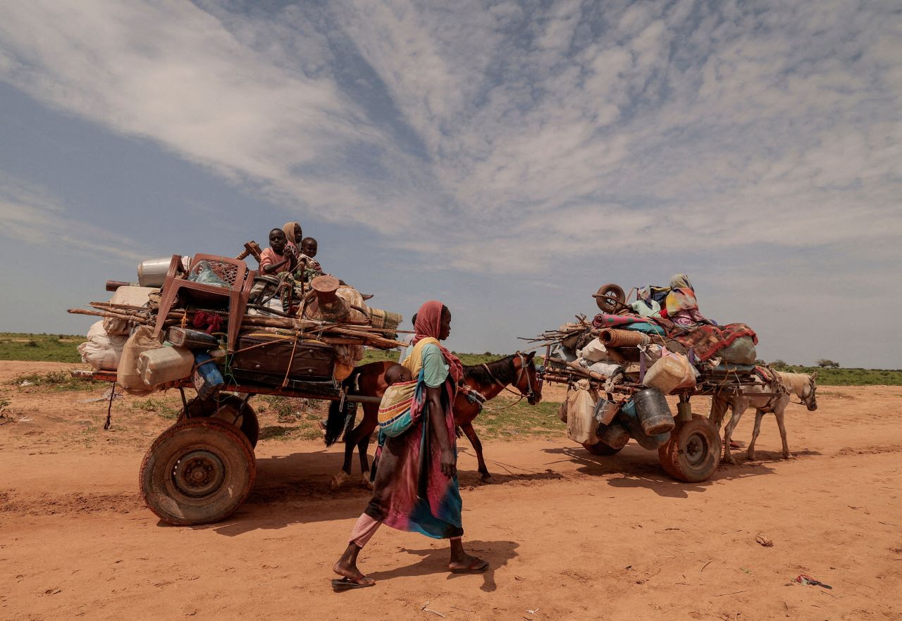 A Sudanese woman who fled conflict in Murnei, in Sudan's Darfur region, walks beside carts carrying her family belongings while crossing the border between Sudan and Chad on Wednesday, August 2.