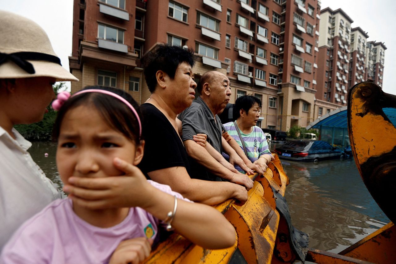 People stand on a front loader while evacuating a flooded residential compound hit by remnants of <a href="https://www.cnn.com/2023/07/31/asia/china-beijing-typhoon-doksuri-khanun-damage-intl-hnk/index.html" target="_blank">Typhoon Doksuri</a> in Zhuozhou, Hebei province, China, on Thursday, August 3.