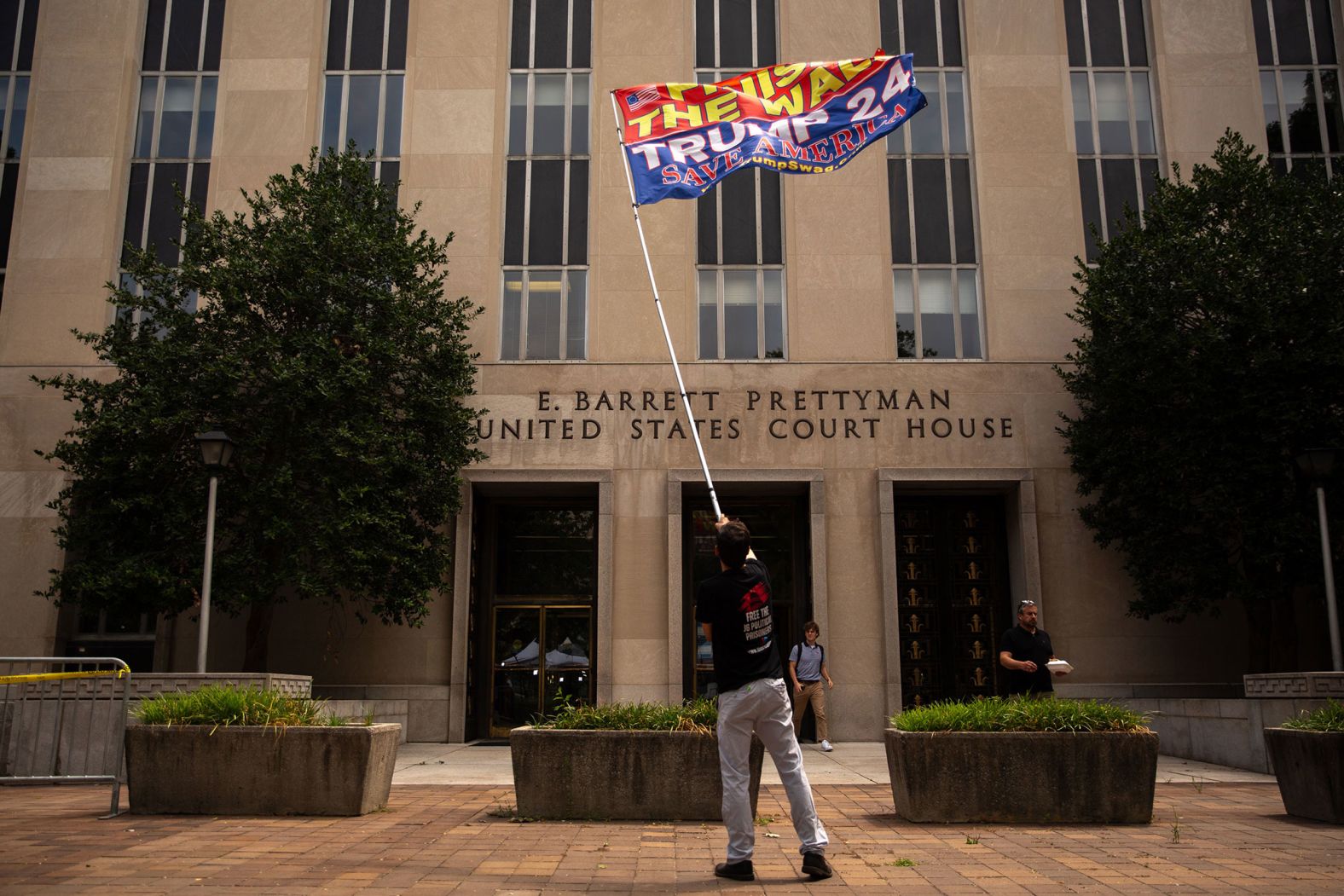 Daniel Demoura, a Trump supporter from Boston, waves a "Trump 2024" flag outside the courthouse.