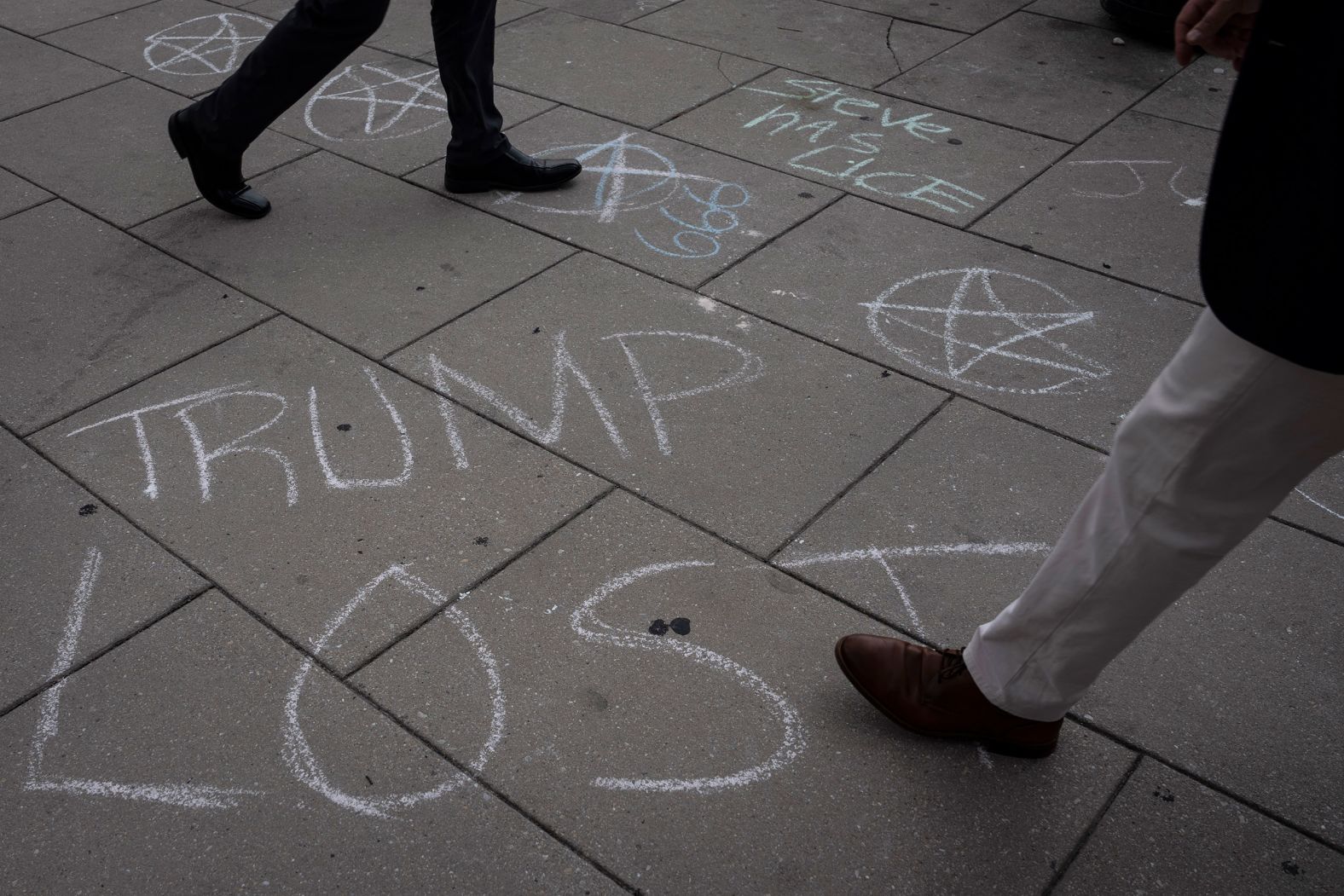 Pedestrians walk by a message written in chalk on the sidewalk outside the courthouse Wednesday, August 2.