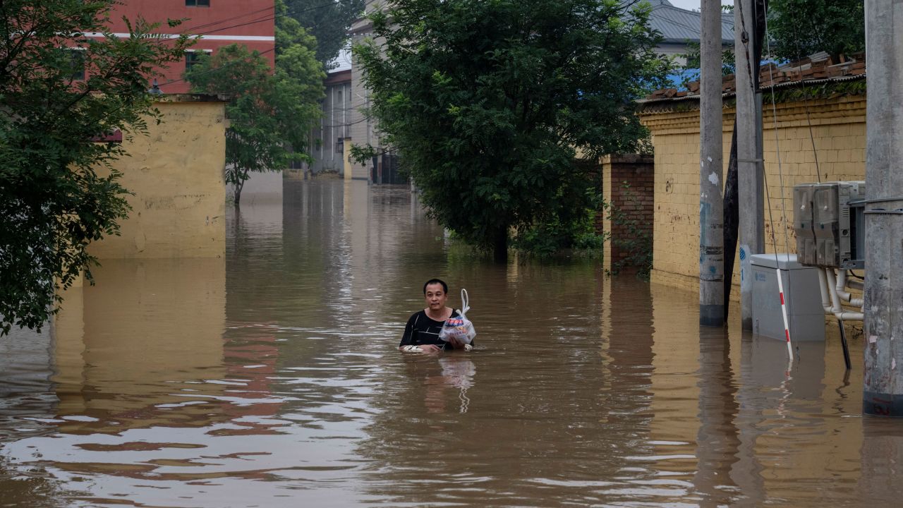A resident wades in chest-deep floodwaters on August 3, 2023, near Hebei province's Zhuozhou city.