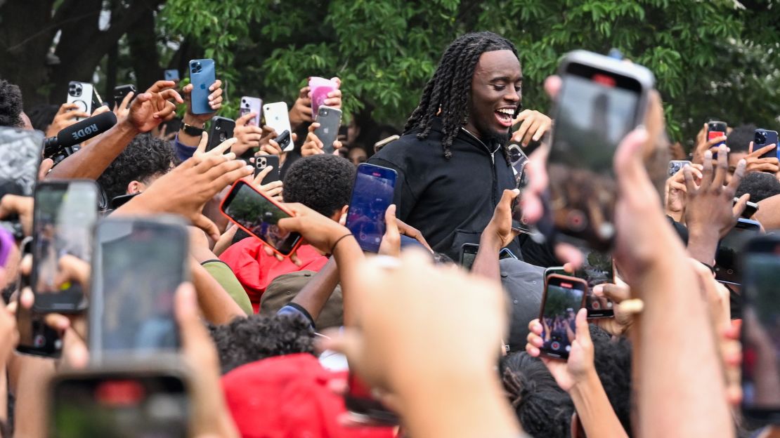 People gather around and cheer for Kai Cenat (C) as members of the NYPD respond to thousands of people gathered for a "giveaway" event on August 4, 2023 in New York City. 