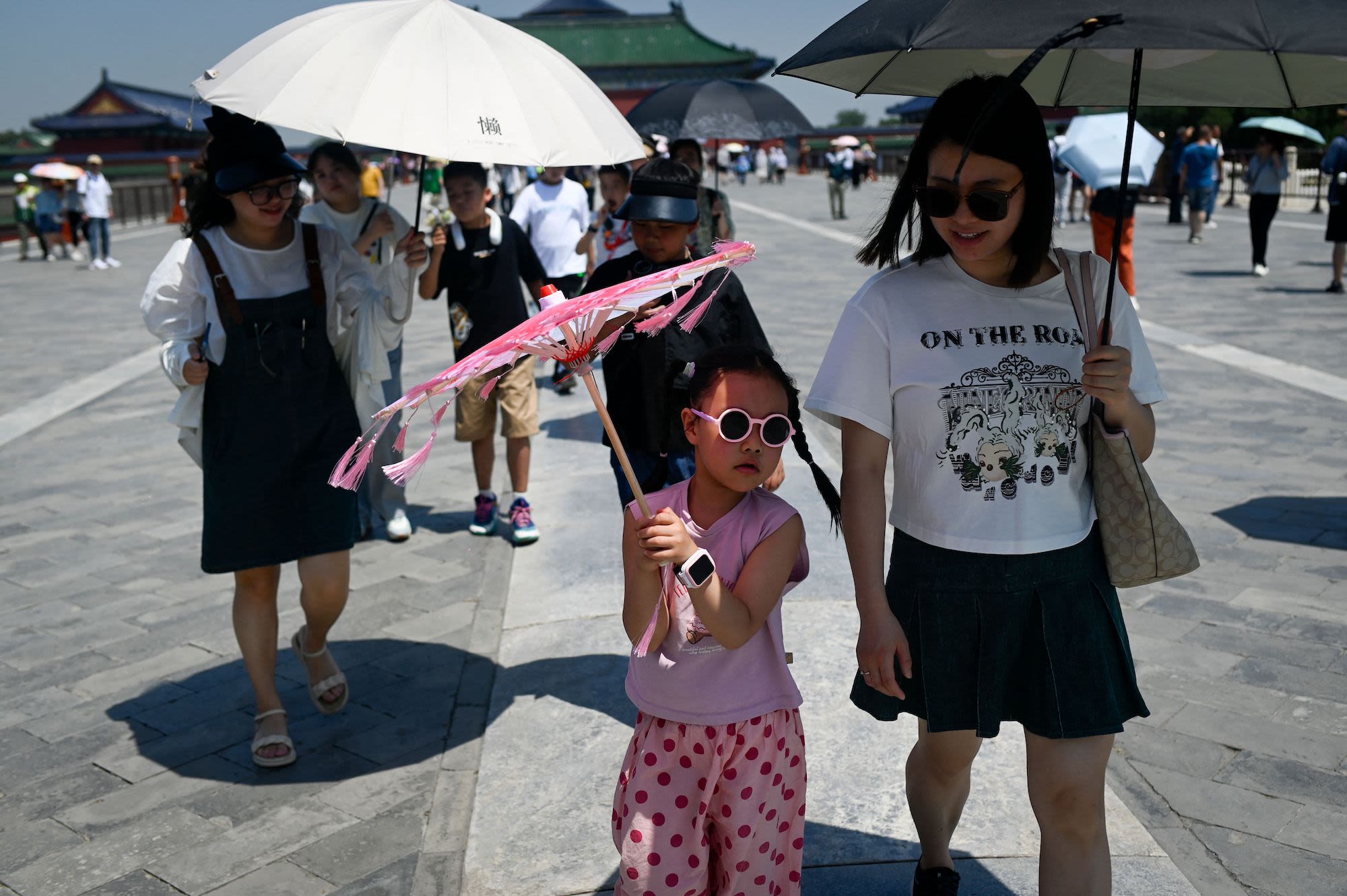 Tourists use umbrellas to shelter from the sun at the Temple of Heaven on a hot day in Beijing on June 30, 2023. (Photo by WANG Zhao / AFP) (Photo by WANG ZHAO/AFP via Getty Images)