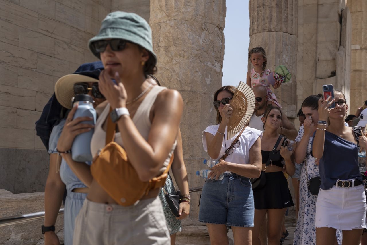 FILE - Tourists visit the ancient Acropolis hill during a heat wave in Athens, Greece, on July 21, 2023. Rebounding travel, especially in the Mediterranean countries that heavily rely on tourism, is expected to support growth in the third quarter as people flock to the beach for their summer holidays in Greece, Spain and Italy, despite recent heat waves and wildfires. (AP Photo/Petros Giannakouris, File)