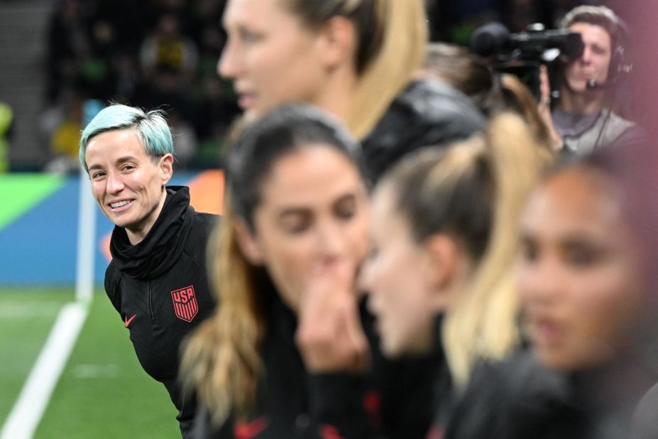 Rapinoe, left, looks on from the substitutes' bench. 