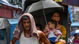 A mother holds an umbrella over her child to escape from hot weather in Kolkata , India, on 3 July 2023. 