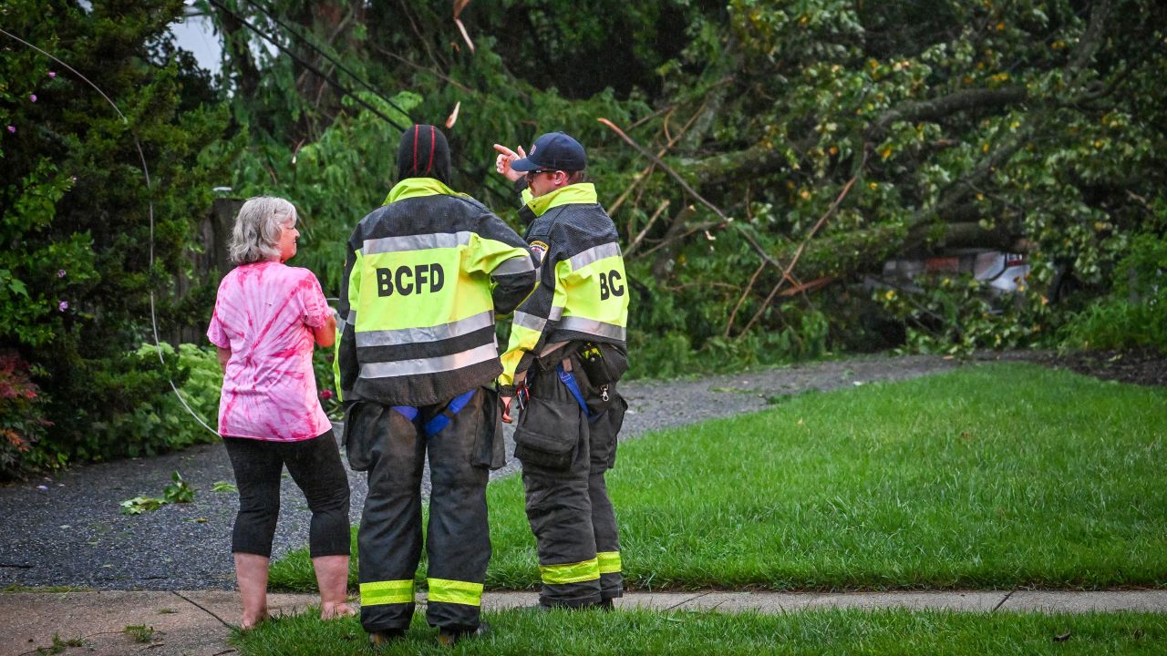 Baltimore County firefighters speak with a resident after several trees took out the power lines and fell on her daughter's car in Towson, Maryland, on Monday.