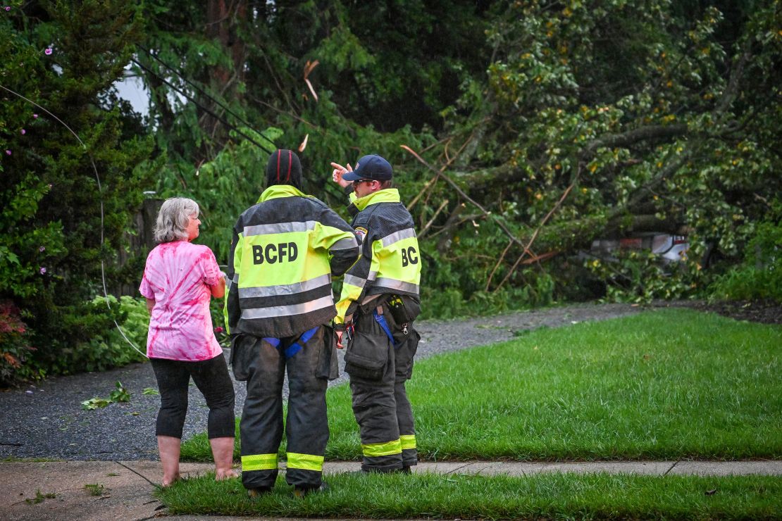 Baltimore County firefighters speak with a resident after several trees took out the power lines and fell on her daughter's car in Towson, Maryland, on Monday.