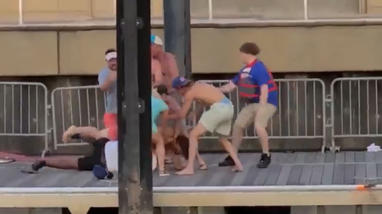 Multiple people stand over and beat a security guard.