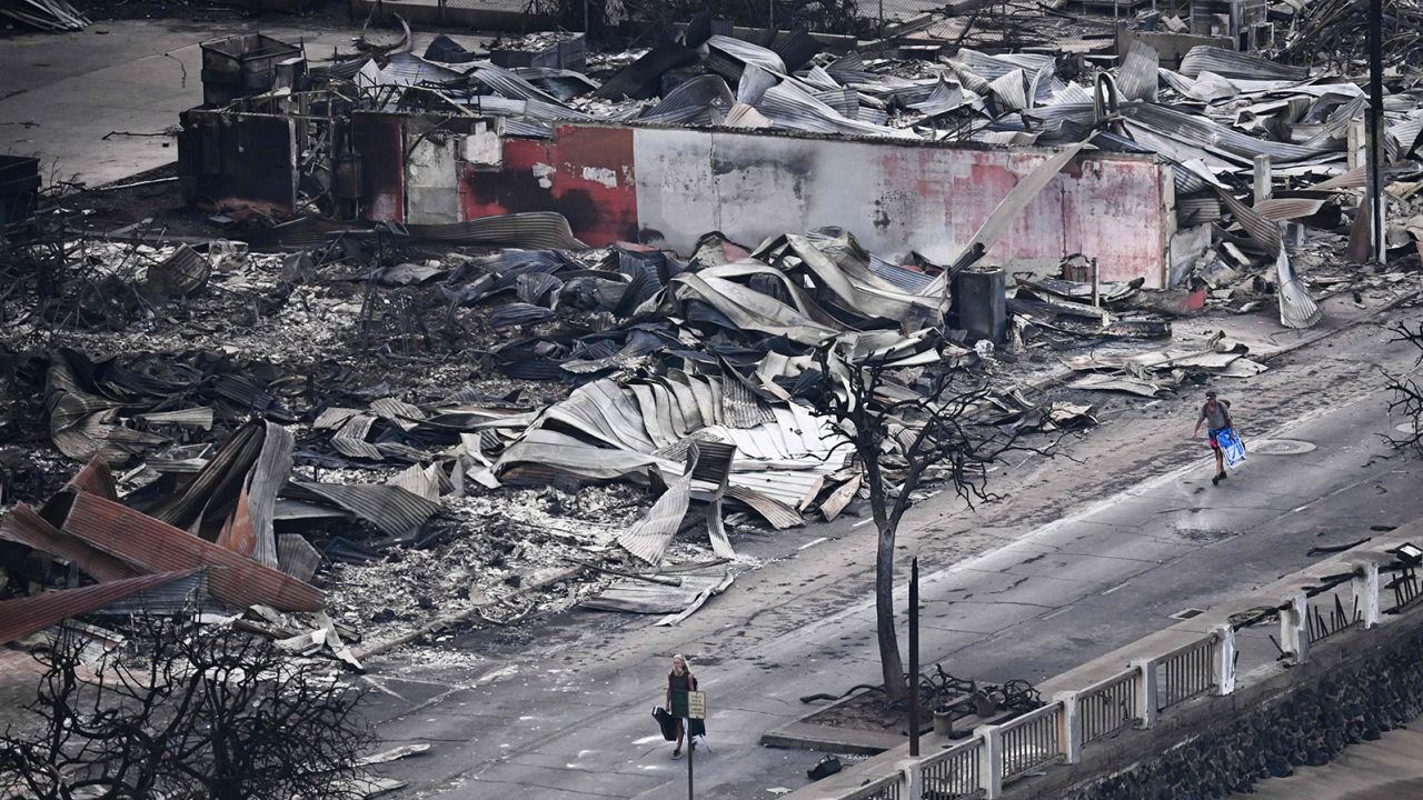 An aerial image taken on August 10, 2023 shows a person walking down Front Street past destroyed buildings burned to the ground in Lahaina in the aftermath of wildfires in western Maui, Hawaii.