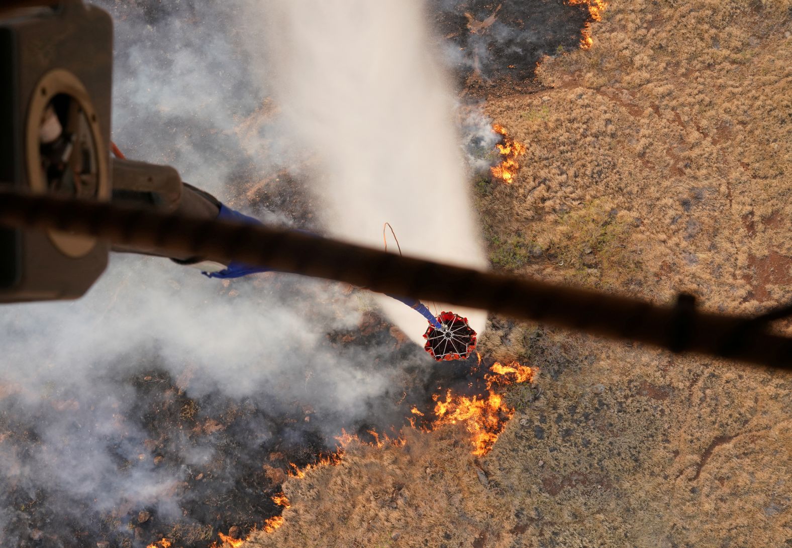 Helicopters with the Hawaii Army National Guard perform water bucket drops to assist in the firefighting efforts on August 9.