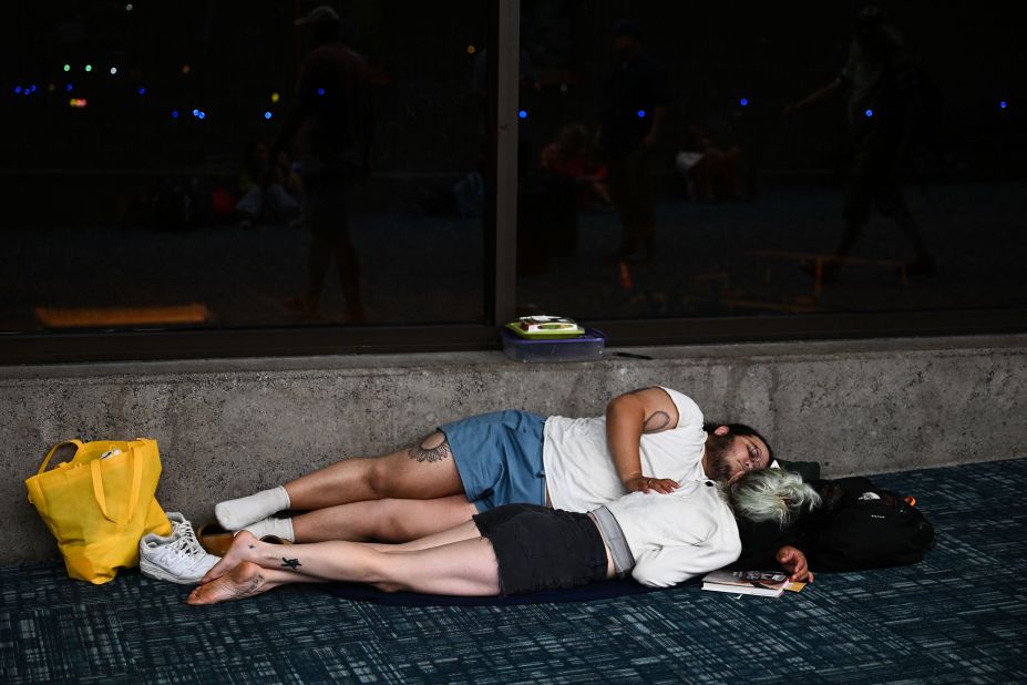 Passengers try to sleep on the floor of Kahului Airport while waiting for delayed and canceled flights off the island from the wildfires in Kahului on Wednesday.