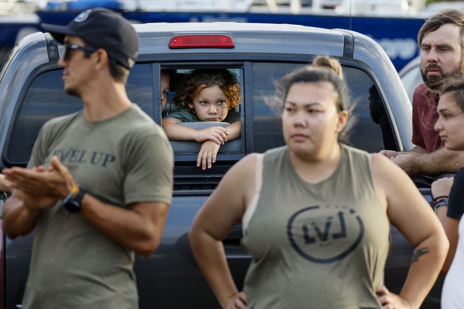 Lianu and Zeran Harris look on as volunteers watch truckloads of donated food and supplies depart for Lahaina in Maalaea, Maui, on Thursday, August 10. Frustrated with the apparently slow response from local government, residents in surrounding communities are collecting donated items and arranging to deliver them to the devastated neighborhoods in Lahaina.