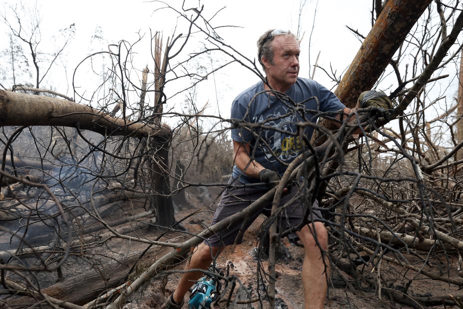 Zoltan Balogh clears away trees that were burned by the wildfire in Kula.