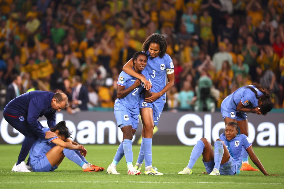 France players sit and stand on the pitch in dejection at the end of the match against Australia.