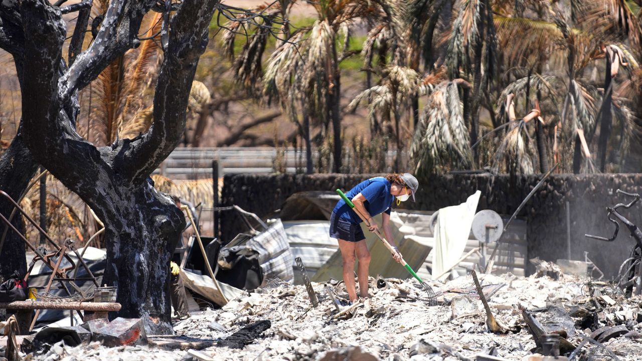 A woman digs through rubble of a home destroyed by a wildfire on Friday, Aug. 11, 2023, in Lahaina, Hawaii. (AP Photo/Rick Bowmer)