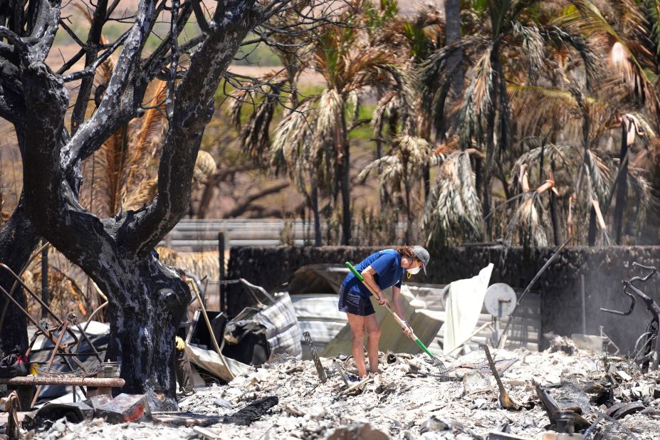 A woman digs through rubble of a home destroyed by a wildfire in Lahaina, Hawaii, on Friday, August 11.