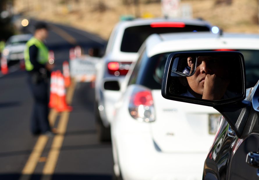 People wait in line at a checkpoint to gain access to Lahaina on Saturday in Wailuku, Hawaii. Local authorities have closed and re-opened a highway allowing access to the area several times since Friday. 