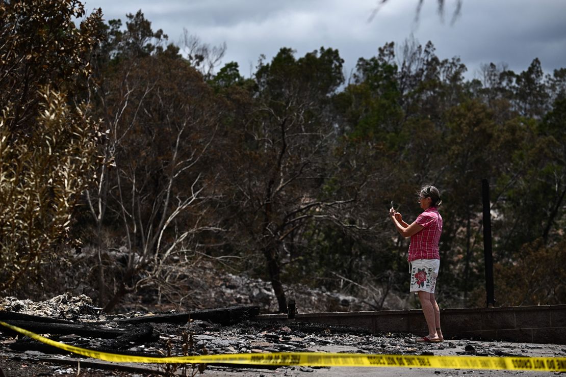 A caretaker photographs the site of a home destroyed by the Maui wildfires in Kula, Hawaii, on Sunday.
