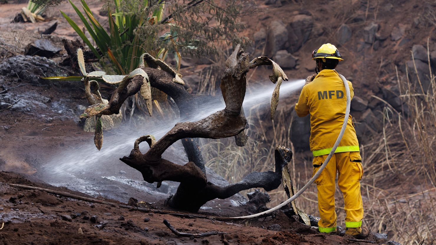 A Maui County firefighter fights flare-up fires in a canyon in Kula on Maui island, Hawaii, August 13, 2023.