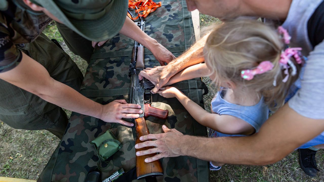 Un militar polaco muestra un arma a los niños durante un festival militar, parte de las celebraciones del Día del Ejército Polaco en Polanka Wielka el domingo.