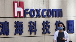 A woman walks past the logo of Foxconn outside the company's building in Taipei, Taiwan November 9, 2022. 