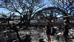 Hano Ganer (Rear, C) and Taylor Ganer (Center Right) look through the ashes of their family's home in the aftermath of a wildfire in Lahaina, western Maui, Hawaii on August 11, 2023. 