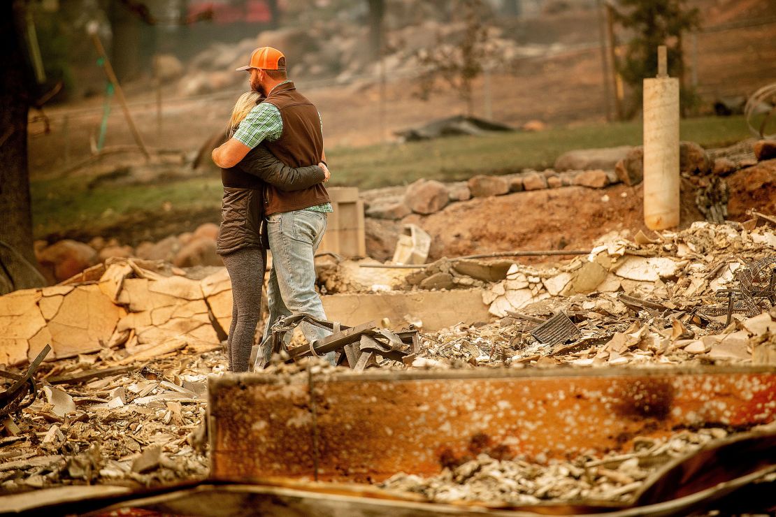 Victims of the Camp Fire embrace while searching through the remains of their Paradise, California, home on November 12, 2018. 