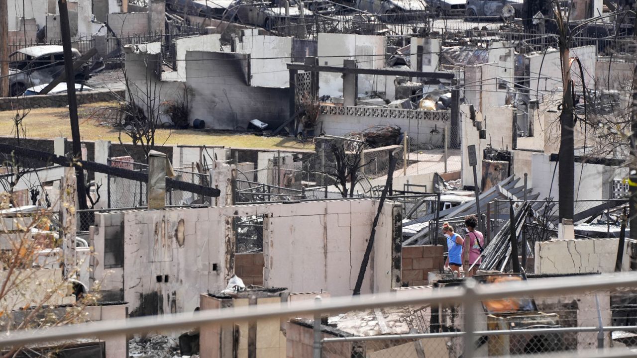 Two people Sunday examine a burned house after an inferno destroyed much of the historic Maui resort town of Lahaina. 