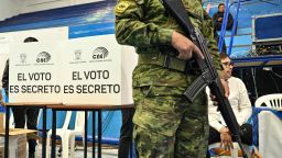 A soldier stands guard next to employees of the National Electoral Council during a drill for next Sunday's presidential elections at the Salesian University in Quito on August 13, 2023. (Photo by MARTIN BERNETTI / AFP) (Photo by MARTIN BERNETTI/AFP via Getty Images)