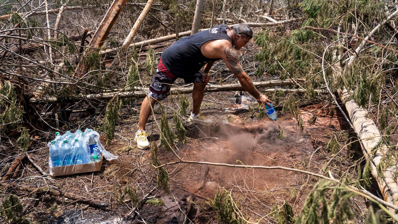 Merrill Kalopodes apaga puntos calientes con agua embotellada en el interior del país de Maui.