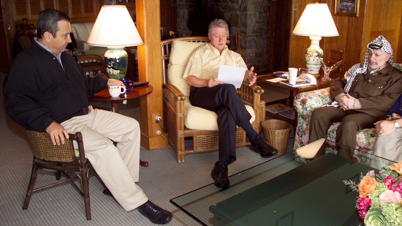 Президентът на САЩ Бил Клинтън, в средата, говори по време на сутрешна среща с израелския премиер Ехуд Барак, вляво, и палестинския председател Ясер Арафат на 25 юли 2000 г. в Кемп Дейвид, Мериленд. Клинтън обяви по-късно през деня, че мирната среща на върха за Близкия изток се е провалила поради задънена улица около статута на оспорвания град Йерусалим. 