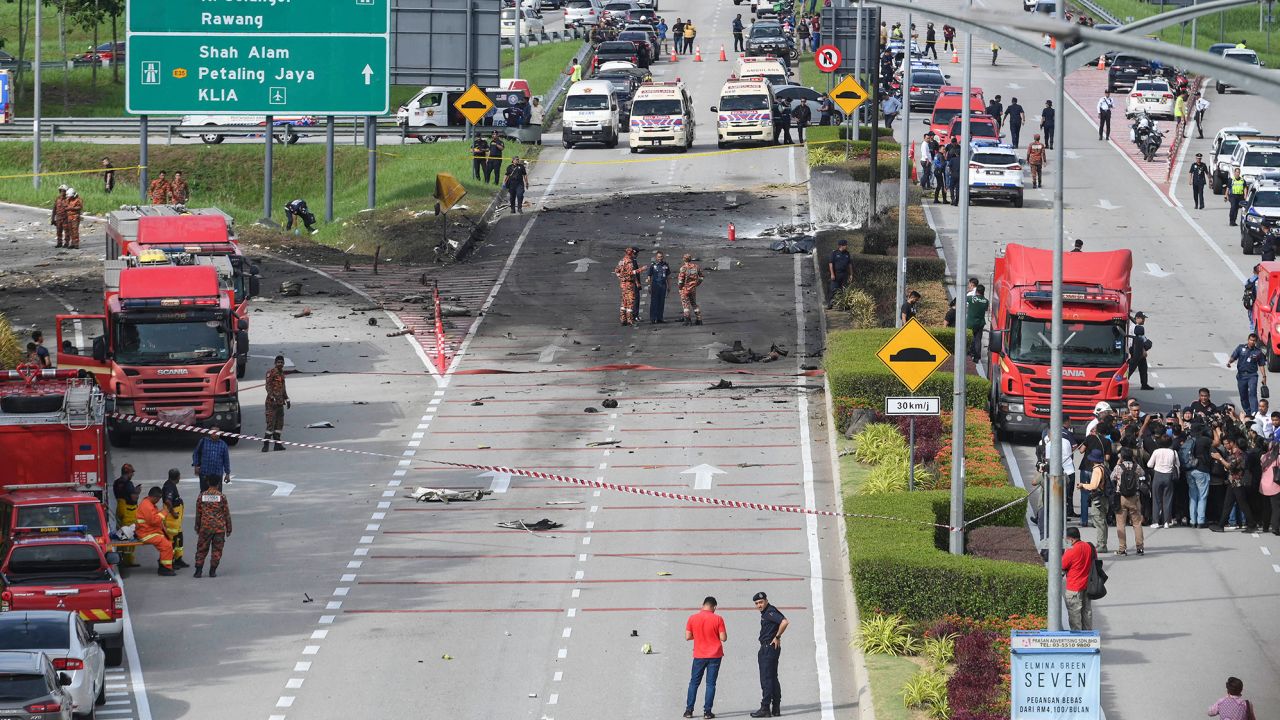Members of the fire and rescue department inspect the crash site of a plane on a street in Shah Alam, Malaysia's Selangor state on August 17, 2023. A light plane crashed on a street in Malaysia's central Selangor state on Thursday, killing eight people on board and two motorists on the ground, authorities said. (Photo by Muhammad Lutfi / AFP) (Photo by MUHAMMAD LUTFI/AFP via Getty Images)