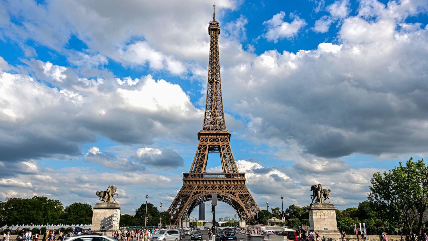Cars drive past the Eiffel Tower in Paris on August 16, 2023. 