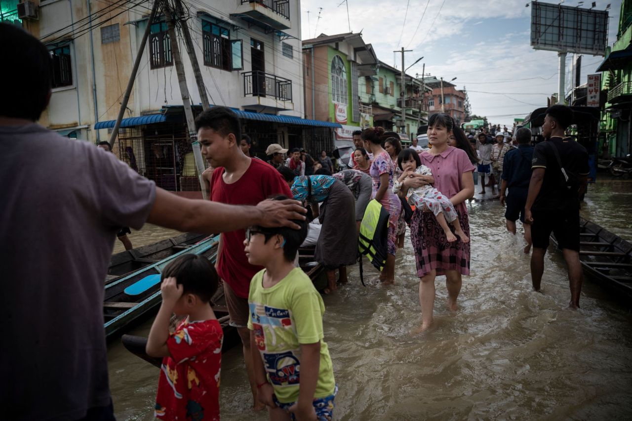 People wade through a flooded street in Bago Township, Myanmar on Friday, August 11. The flooding was caused by monsoon rains.