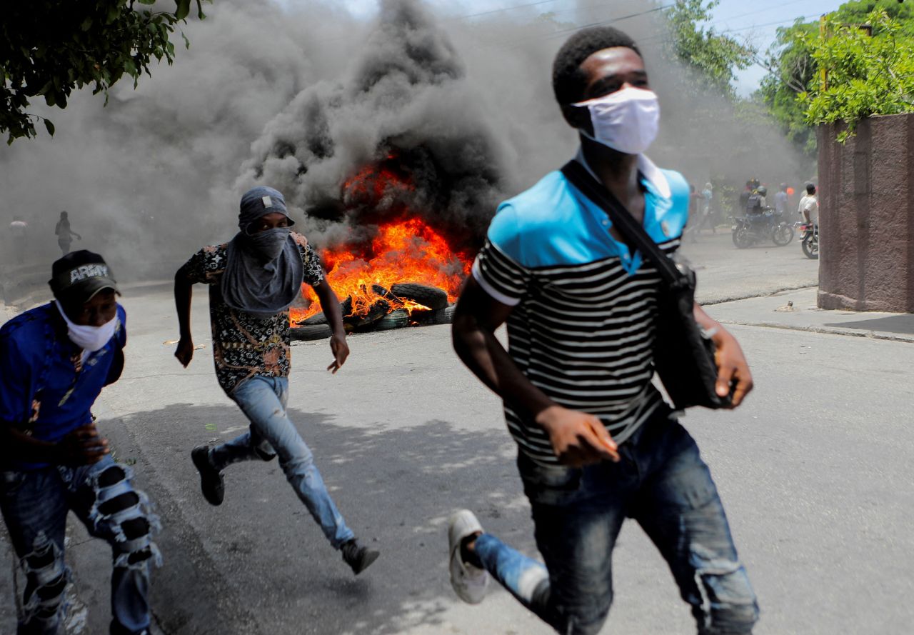 Men run next to burning tires in Port-au-Prince, Haiti, during a protest demanding an end to gang violence on Monday, August 14. Port-au-Prince and surrounding areas have been gripped by a <a href="https://www.cnn.com/2023/08/09/americas/haiti-us-nurse-daughter-freed-intl/index.html" target="_blank">yearslong kidnapping-for-profit epidemic</a>, with hundreds of Haitians targeted by gangs seeking ransom payments each year.